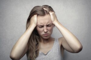 Woman holding hands to her head and looking stressed